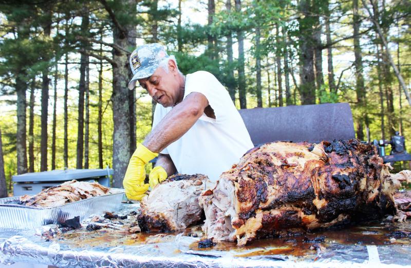 Paul Fernandes carves a roast pig at the event, held at the Dudley Brown VFW in Onset. BY MATTHEW BERNAT